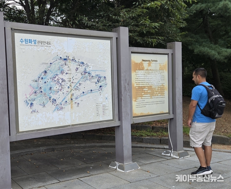 세계문화유산 수원화성, 방치된 나무·낡은 안내판·파손된 도로… 수원시의 ‘부끄러운 관리’ (사진 - 8월23일, 외국인이 팔달산 구간 성곽 입구에 설치된 ‘수원화성 관광안내도’를 보고 있다. 도색이 벗겨지고 글씨가 바래 가독성이 크게 떨어졌다 / 김교민 기자