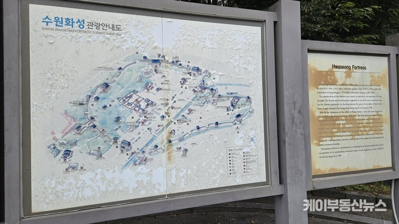 세계문화유산 수원화성, 방치된 나무·낡은 안내판·파손된 도로… 수원시의 ‘부끄러운 관리’ (사진 - 8월23일, 외국인이 팔달산 구간 성곽 입구에 설치된 ‘수원화성 관광안내도’를 보고 있다. 도색이 벗겨지고 글씨가 바래 가독성이 크게 떨어졌다 / 김교민 기자