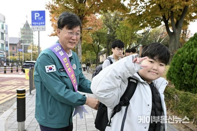 이민근 안산시장(사진 왼쪽)이 학현초등학교 앞에서 ‘스쿨존 어린이 교통안전 캠페인’을 진행하며 등교하는 어린이의 가방에 '홍이 키링'을 달아주고 있다.