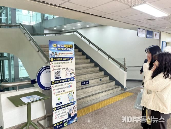 수원시 공직자들이 직원복지통합플랫폼, 인공지능 챗봇 등을 안내하는 홍보물을 보고 있다.